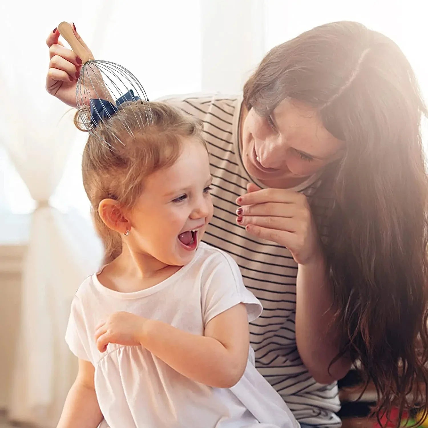 Woman using a 24-finger metal octopus head massager with wooden handle to relax a smiling child's scalp at home.