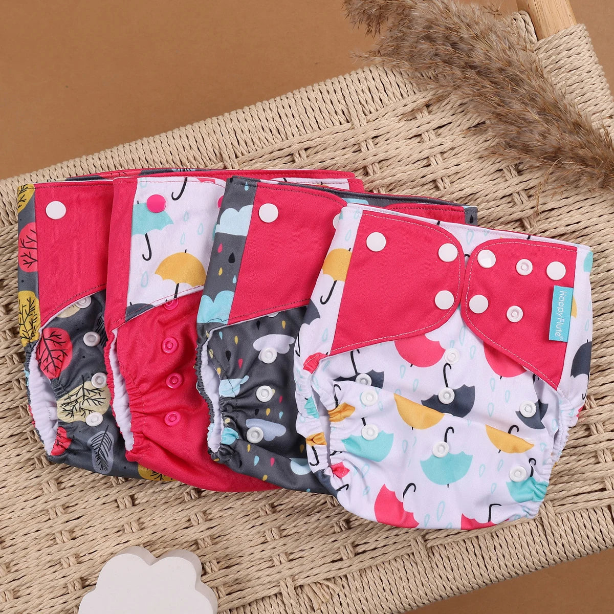 Set of 4 Happy Flute reusable cloth baby diapers with colorful umbrella and rain patterns on a wicker chair.