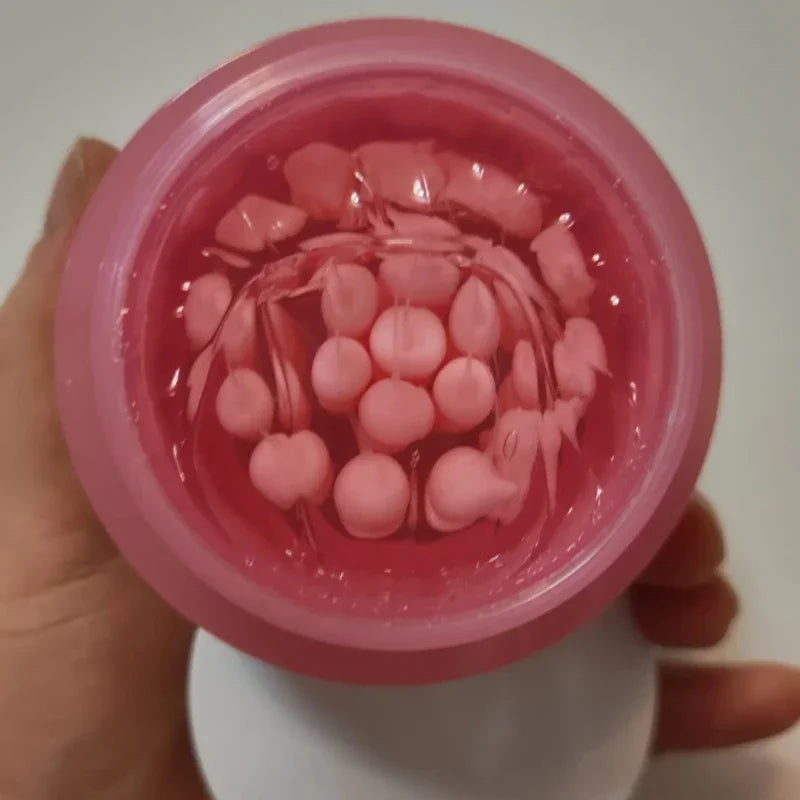 Open jar of pink Korean face cream containing suspended pink collagen capsules in a clear, lightweight gel base.