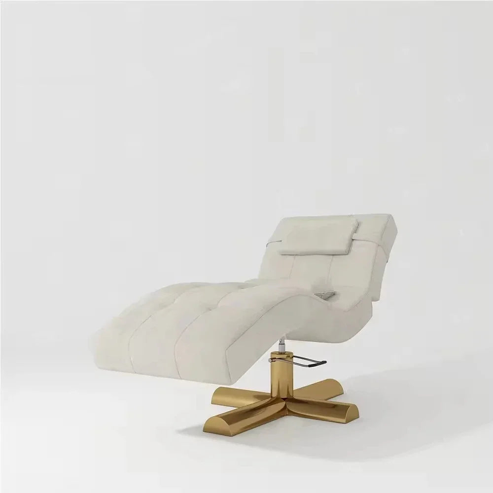 Cream tufted facial bed with a gold cross base and adjustable height lever for professional spa and salon use.