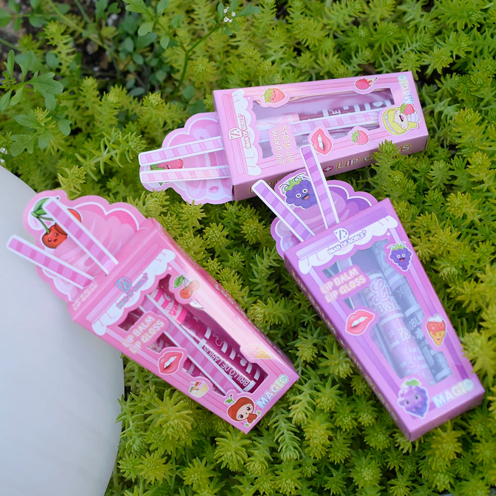 Cute ice cream-shaped lip gloss and balm set in pink and purple packaging on a green plant background.