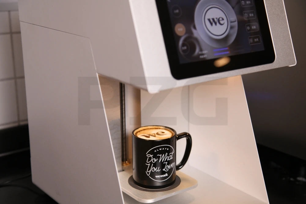 White digital coffee printer machine with touch screen printing WeWork logo foam art on a black ceramic mug.