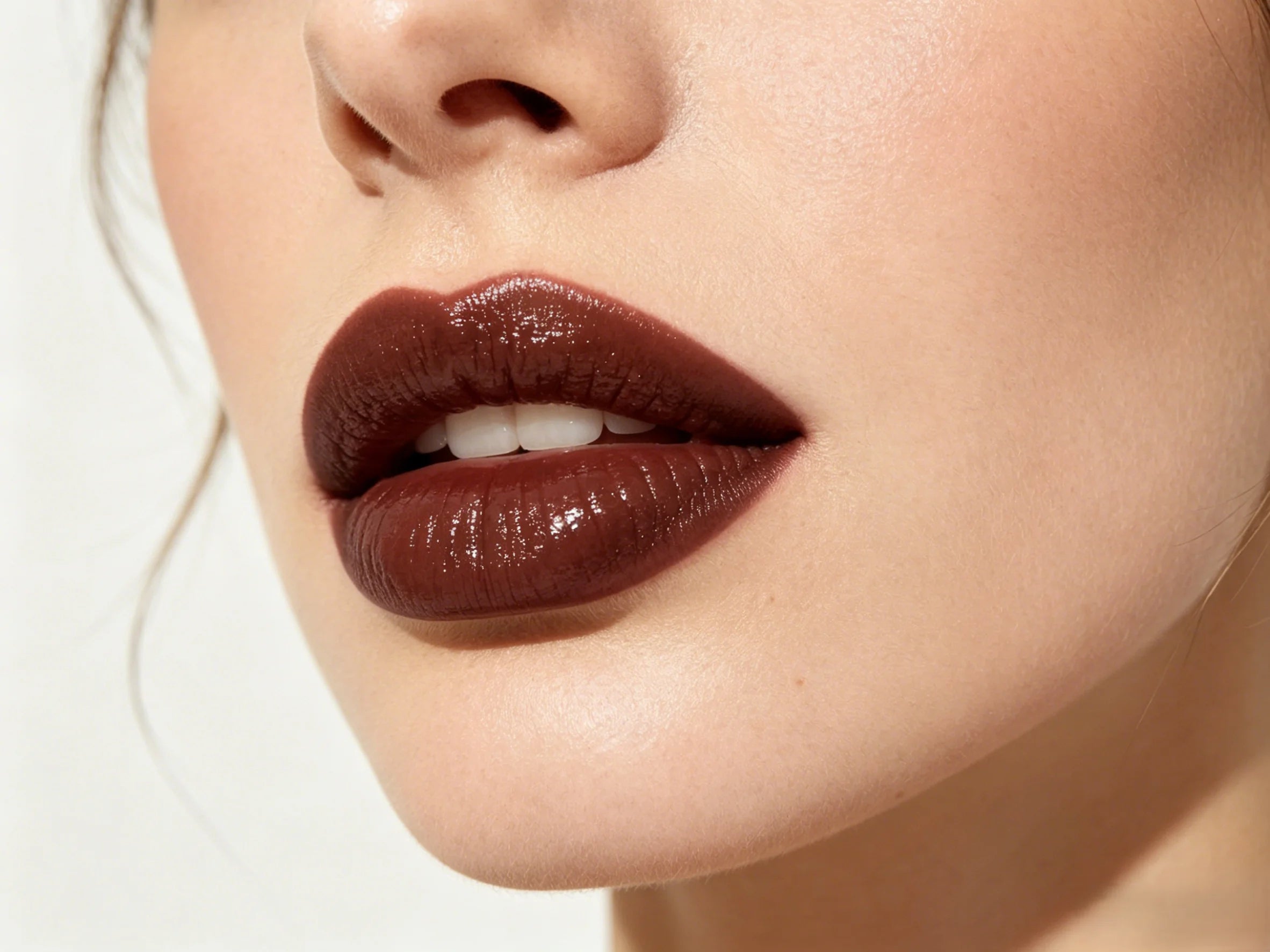 High-shine dark brown moisturizing lip gloss on model lips for a hydrating Western makeup look.