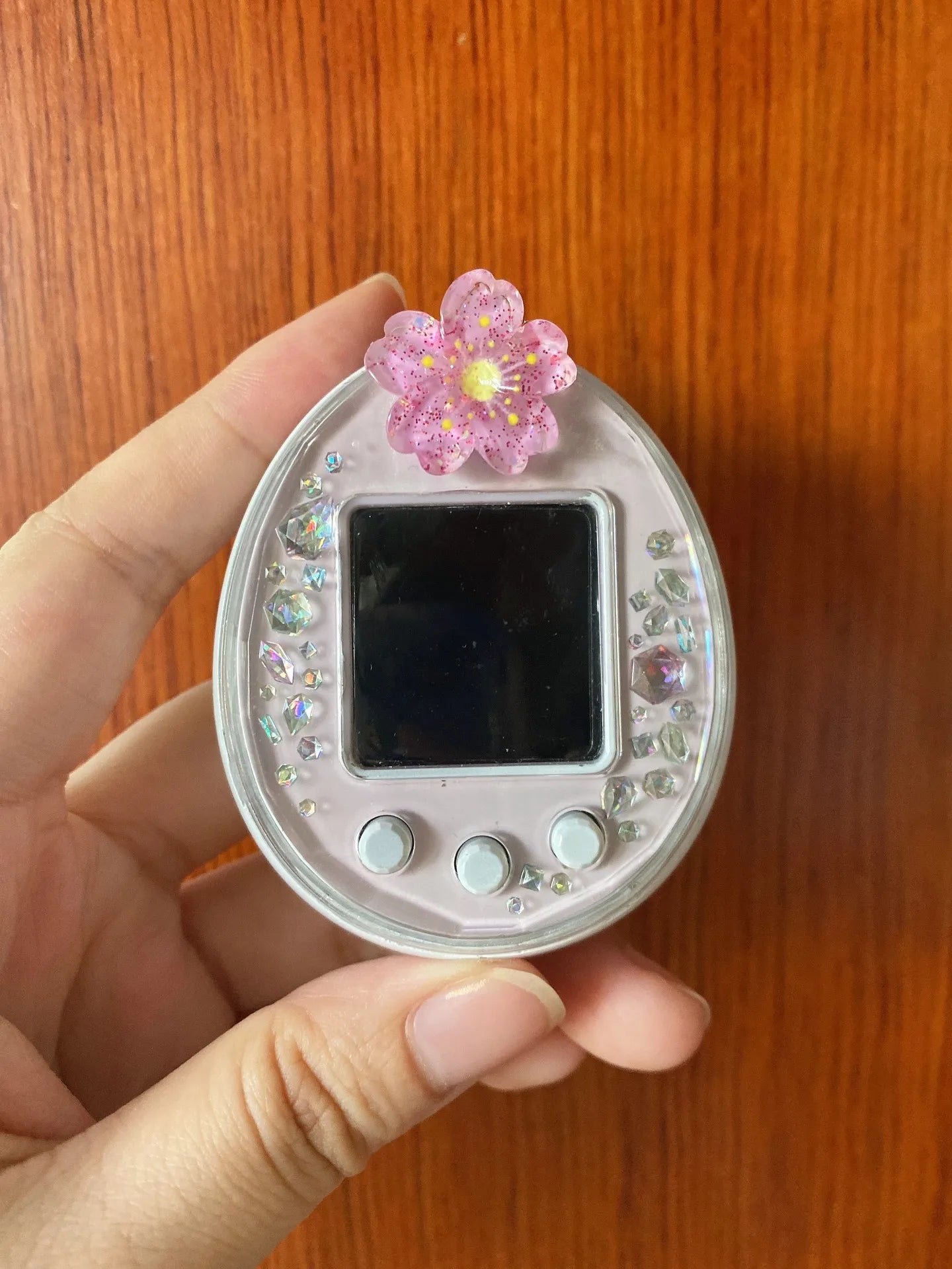 Tamagotchi Uni hard shell case with pink cherry blossom charm and crystals for dust protection and aesthetic style.