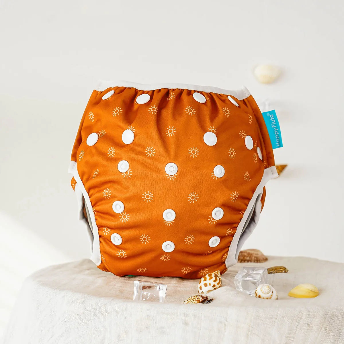 Happy Flute reusable cloth diaper in burnt orange with white sun print pattern, adjustable baby care essential.