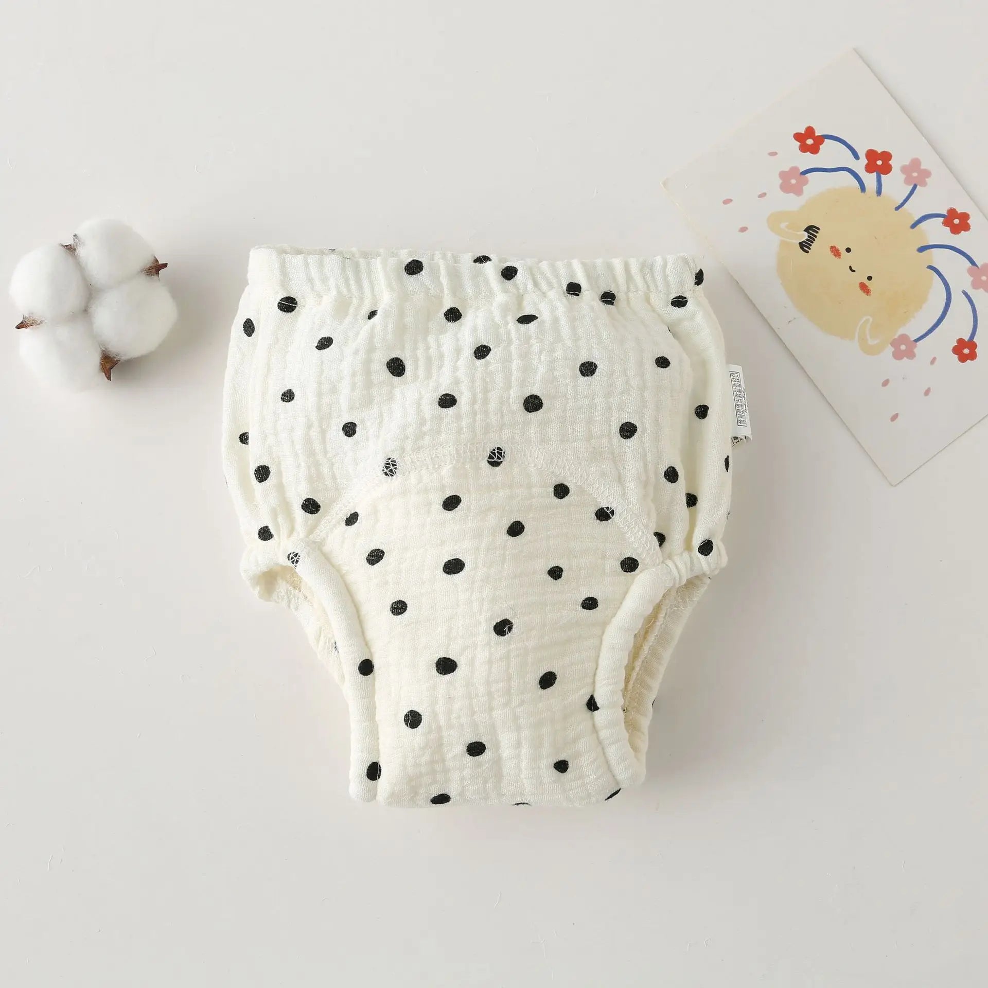 Cotton muslin baby training diaper with black polka dot print on white fabric.