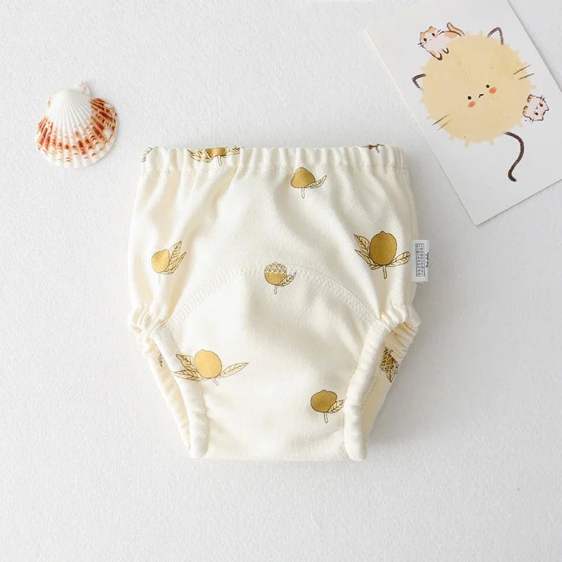Cream-colored baby training diaper with gold lemon print, soft cotton material for infant care.