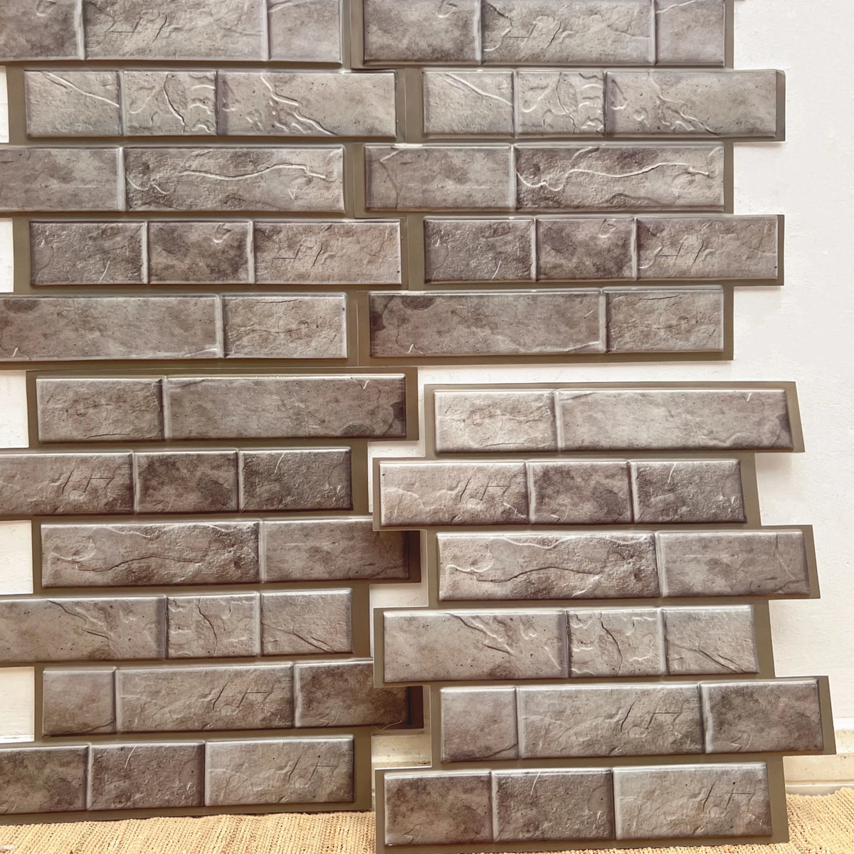 Peel-and-stick backsplash tile sheet with faux brick pattern in gray and taupe tones