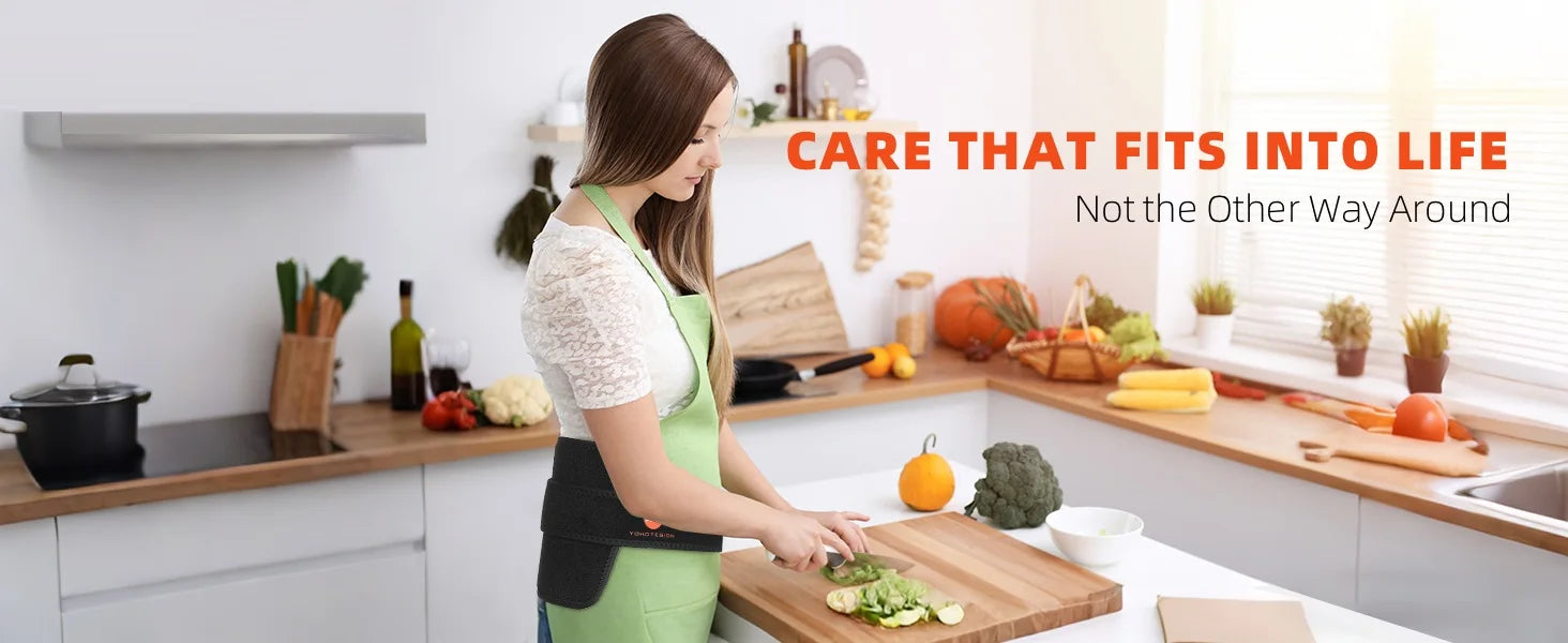Woman wearing a portable black red light therapy belt with 660nm and 850nm infrared LEDs while cooking in kitchen.