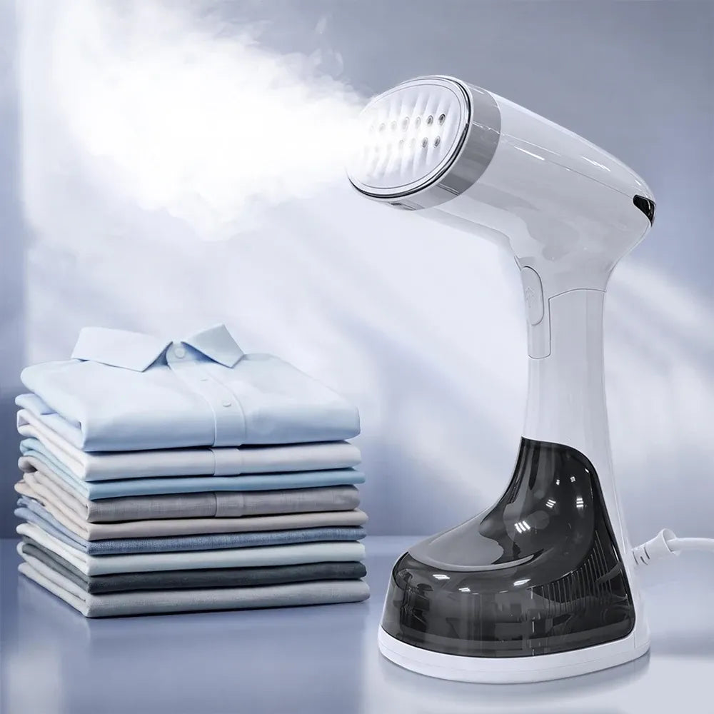 Handheld garment steamer releasing powerful steam next to a neatly folded stack of shirts.