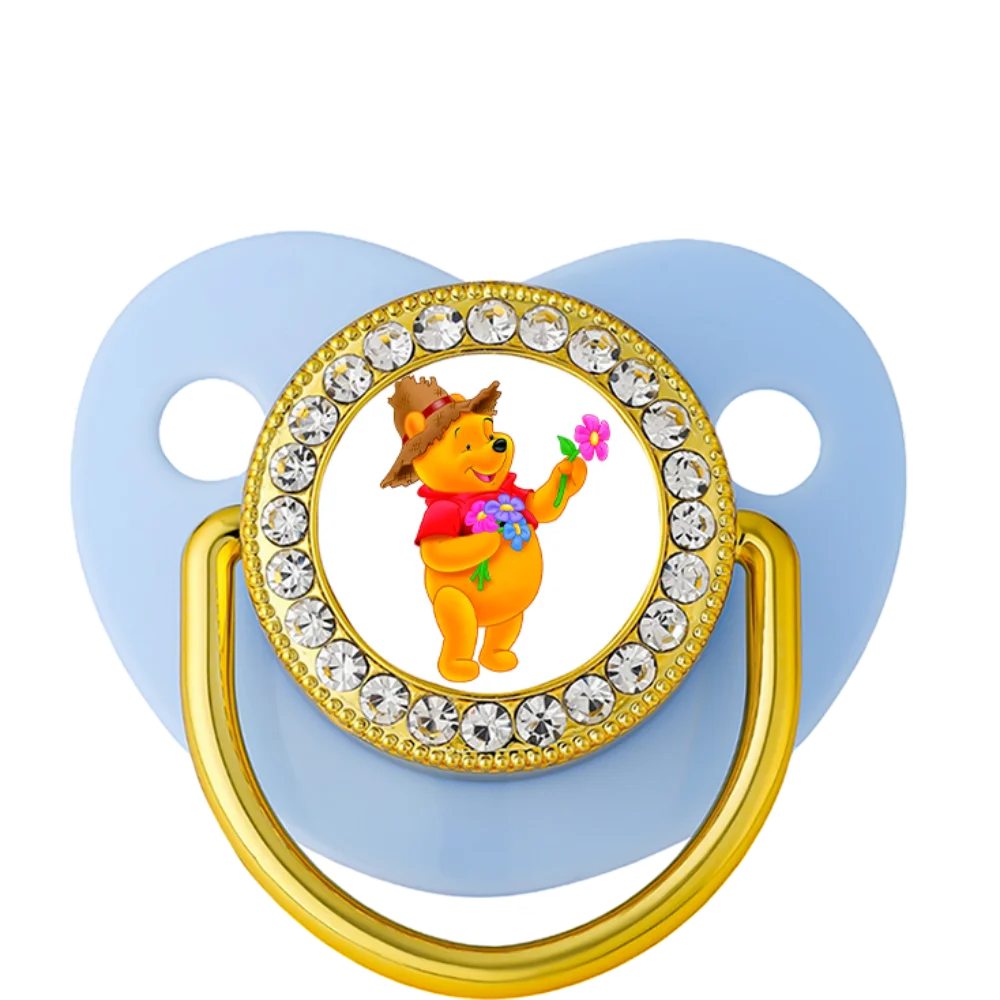 Light blue silicone baby teething pacifier with Winnie the Pooh design and gold details for teething relief.