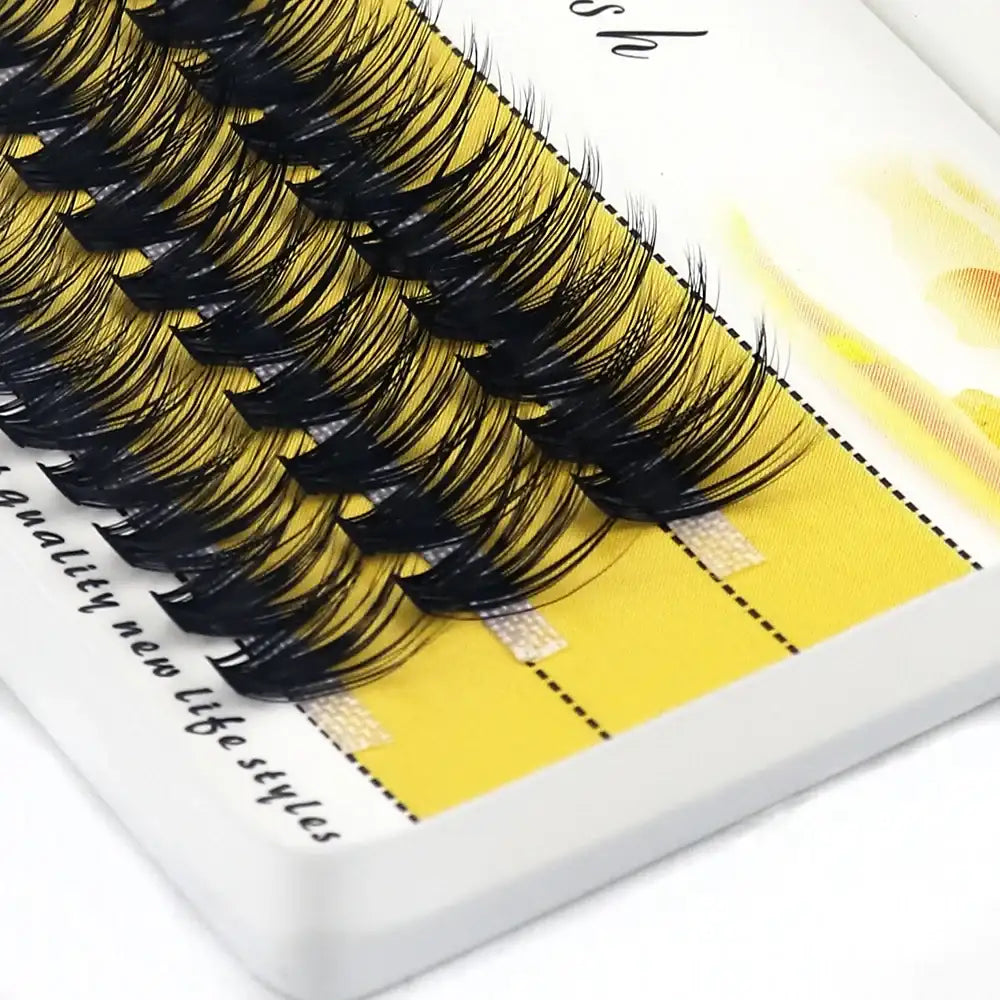 Black 3D mink individual eyelash clusters arranged in rows on a yellow adhesive tray.