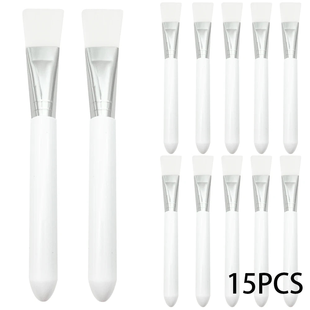 A set of 15 white silicone facial mask brushes with silver metal ferrules and smooth white handles.