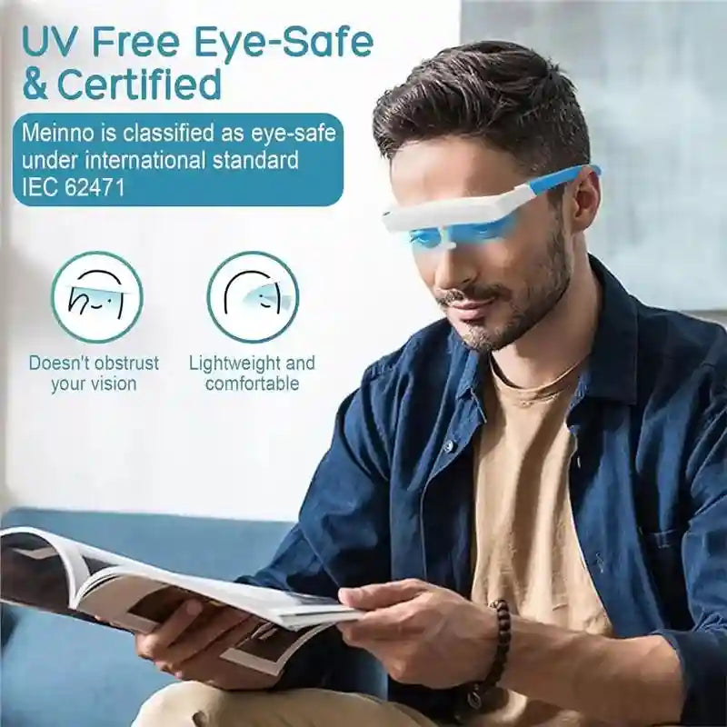 A man wearing blue and white portable light therapy glasses while reading a book.
