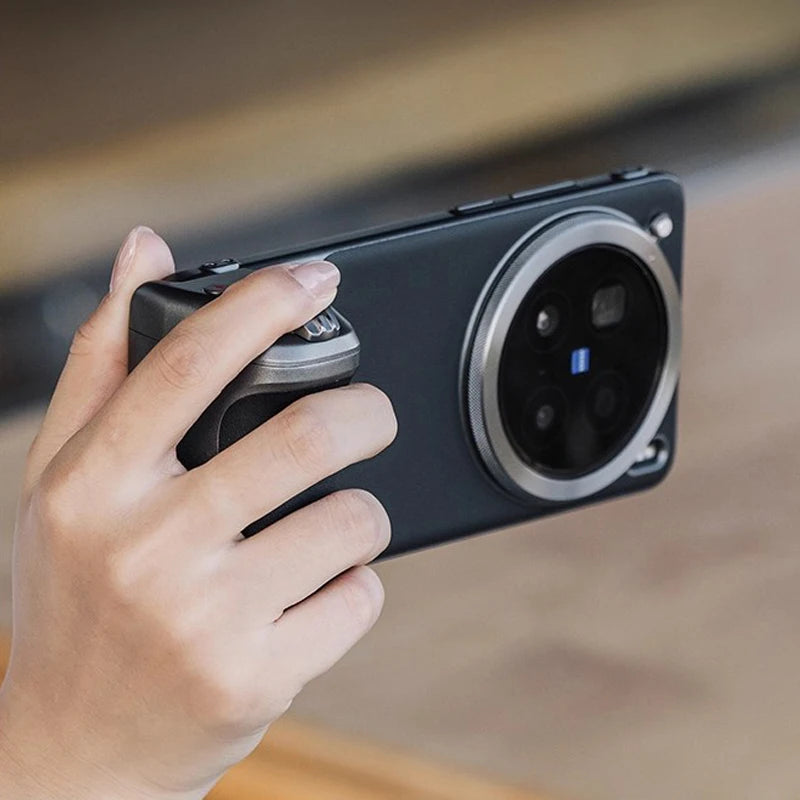 Smartphone camera grip with a matte black finish and silver shutter button, attached to a phone for steady photography.