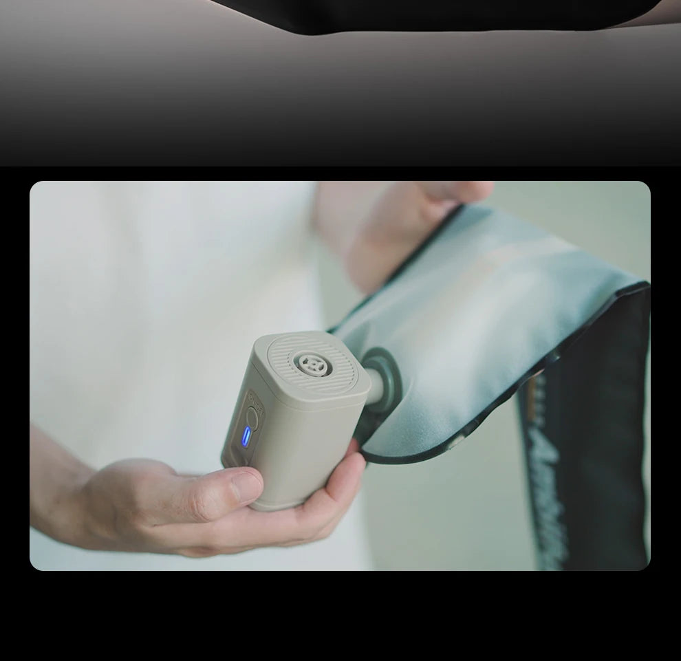 Small, beige portable air pump inflating a light blue fabric compression wrap for massage or recovery.