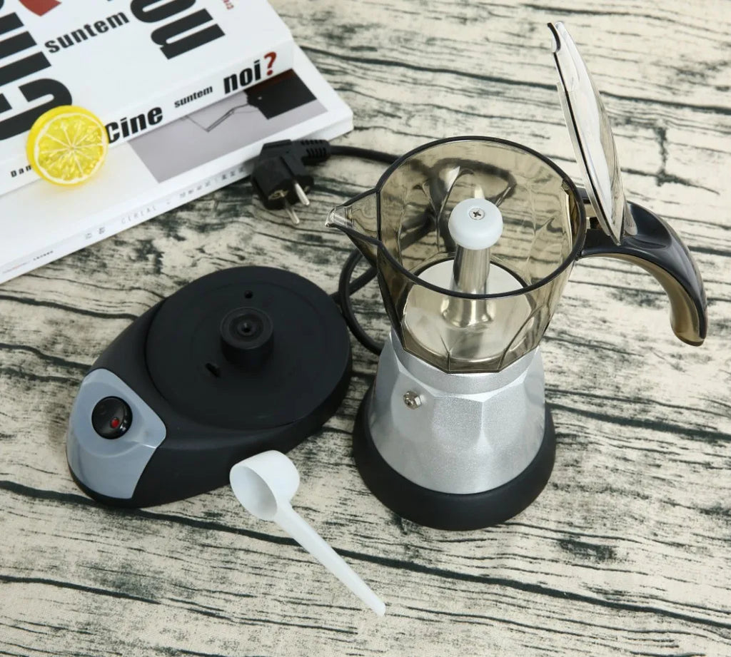 Electric moka pot with silver metal base, transparent top, and black power station with on/off switch and spoon.