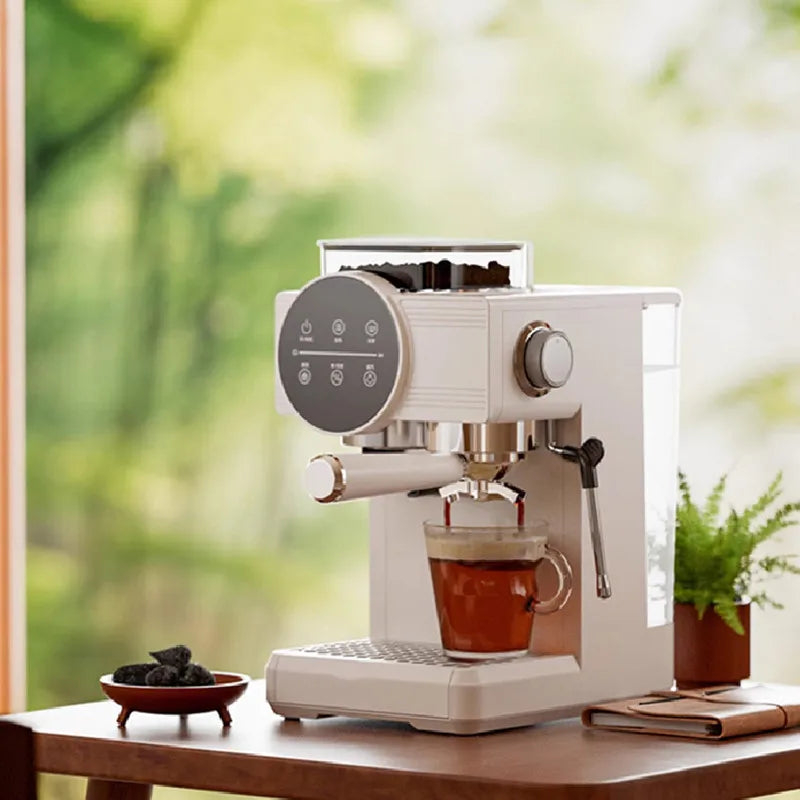 Compact beige espresso machine with digital touch display, integrated bean hopper, and steam wand brewing into a mug.