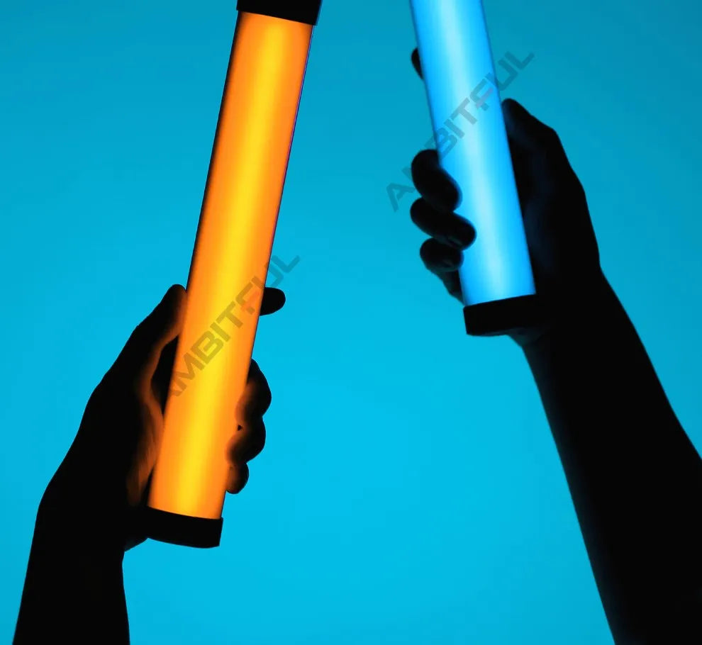 Two handheld LED light wands, one orange and one blue, held by hands against a matching blue background.