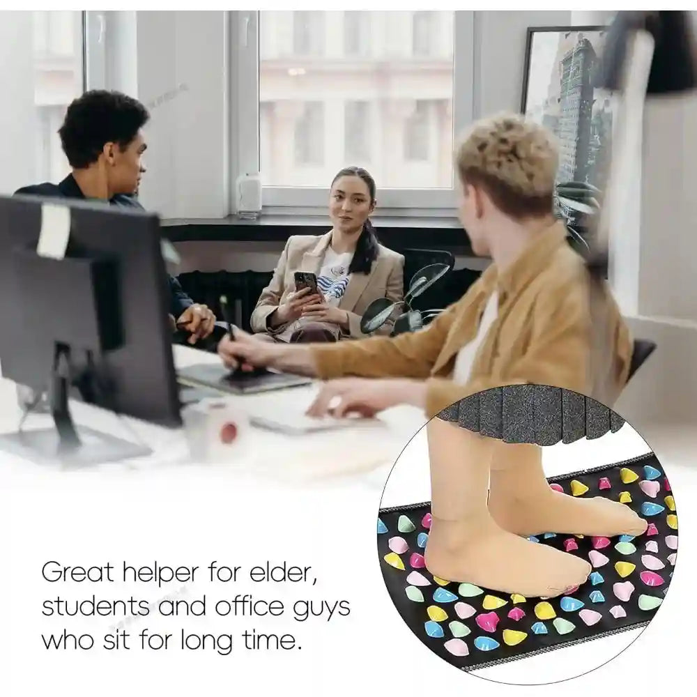 Person standing on black acupressure foot massage mat with colorful stone-shaped nodes for reflexology pain relief.