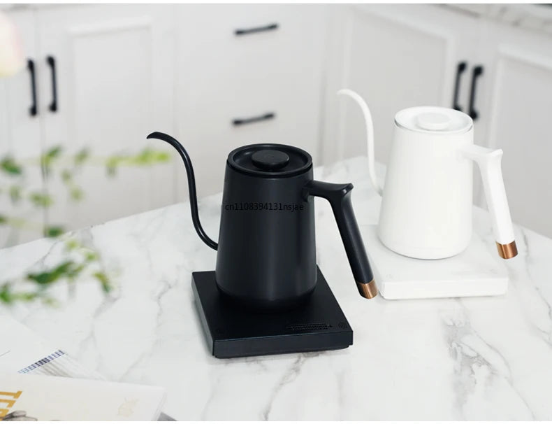 Modern matte black and white electric gooseneck kettles with copper accents on a kitchen marble countertop.