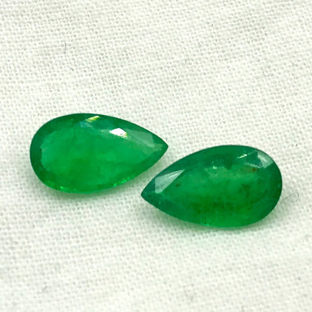 Two green oval-teardrop gemstone cabochons, smooth polished look
