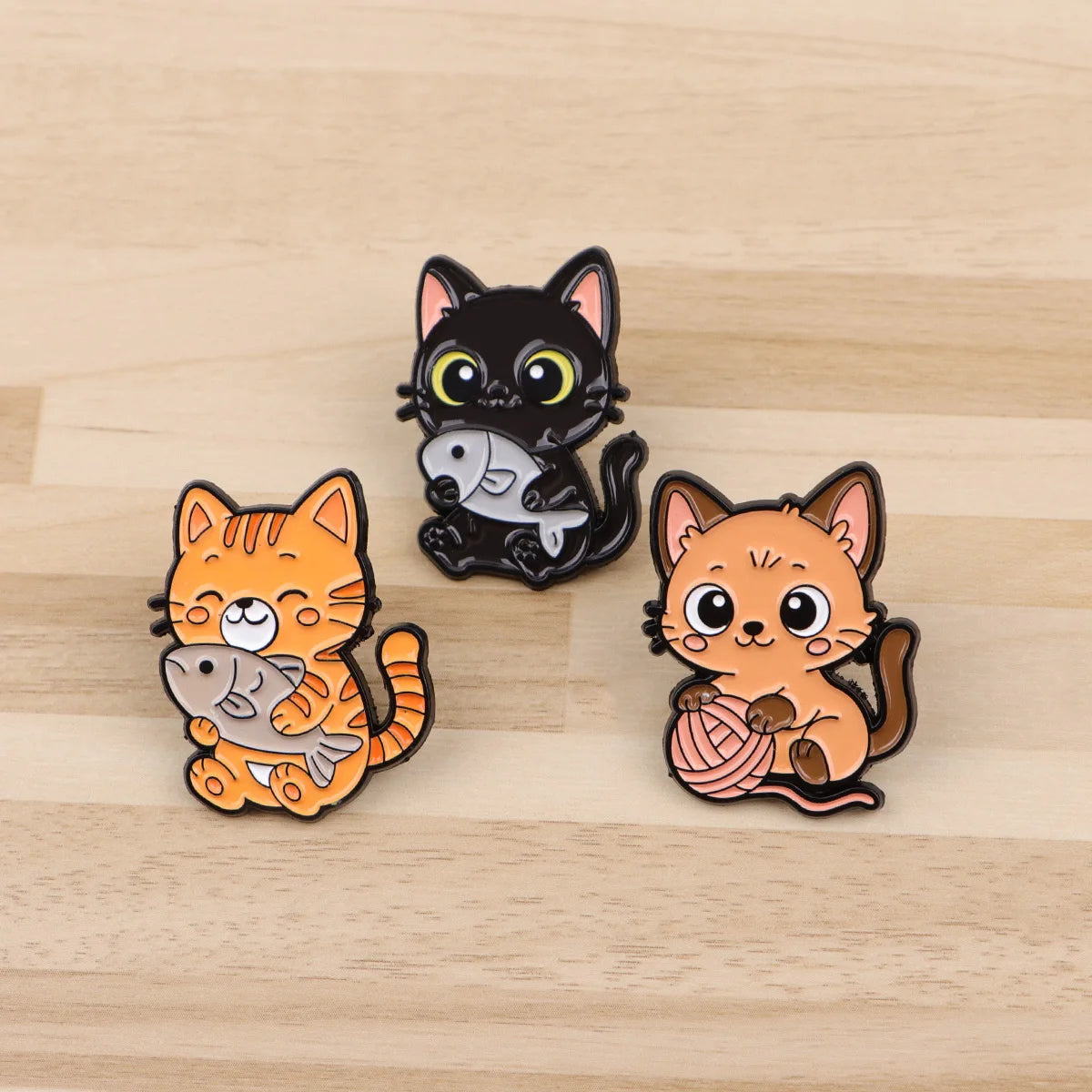 Cute cat enamel pins, featuring black and orange kittens with fish and yarn, perfect for backpacks or lapel accessories.