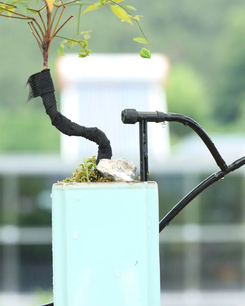 Black micro dripper with adjustable flow delivering a directed stream from hose line