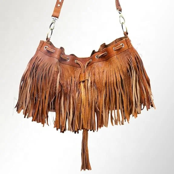 Tan leather fringe bucket bag with drawstring closure, convertible shoulder and crossbody strap. Boho style trunk bag.