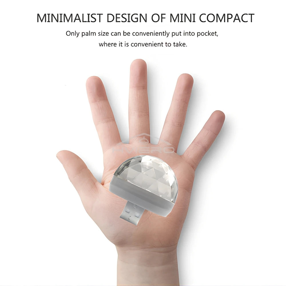 Small, faceted, clear plastic dome disco light with a USB connector, held in a person's palm for scale.