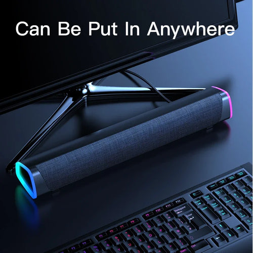 Portable speaker bar on desk with gray fabric grille and glowing RGB side light