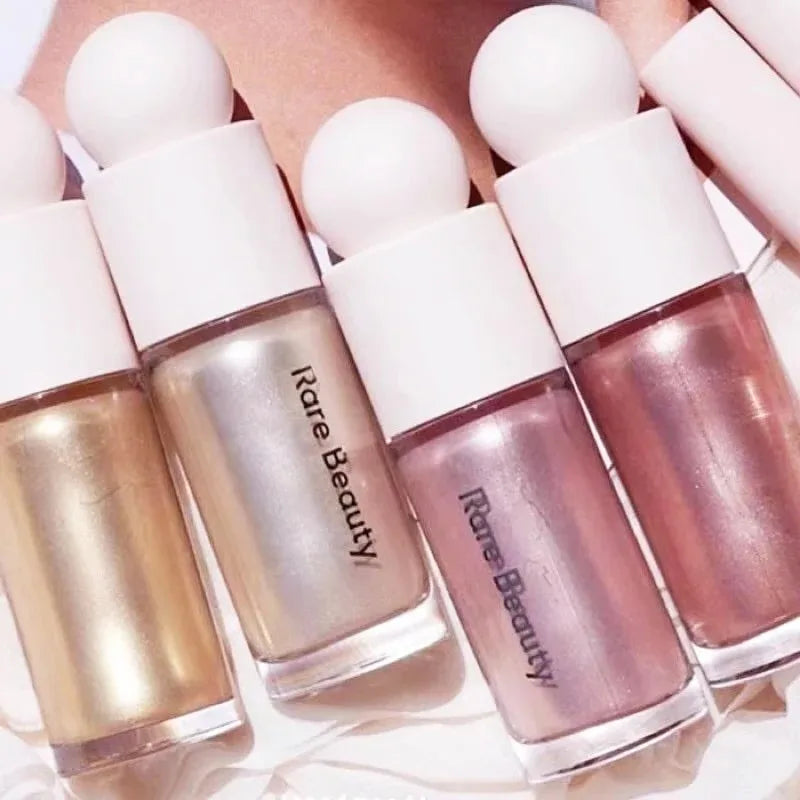 Rare Beauty liquid highlighters in shimmer gold, champagne, and rose pink shades with sleek, waterproof bottle designs.