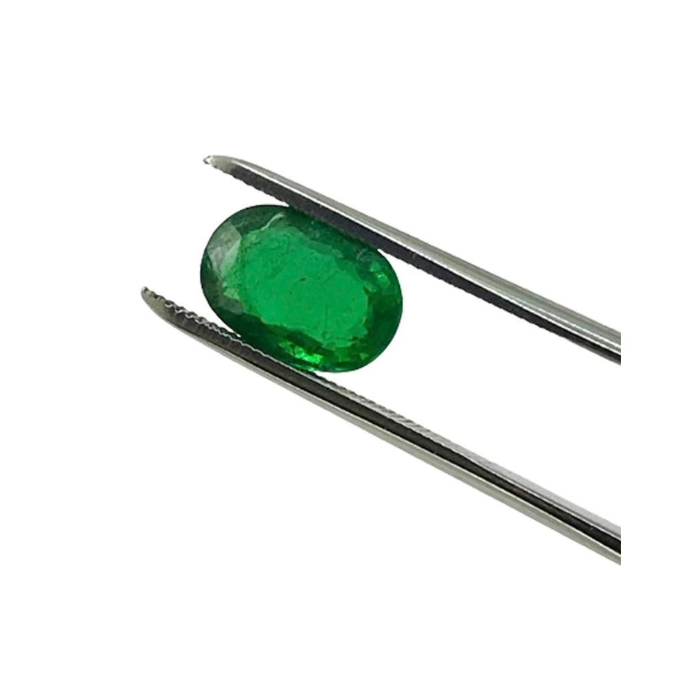 Green oval faceted gemstone held by metal tweezers, loose stone