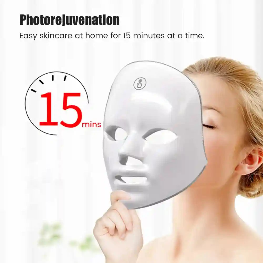 Woman holding a smooth white facial LED mask with cutouts for eyes, nose, and mouth next to her face.