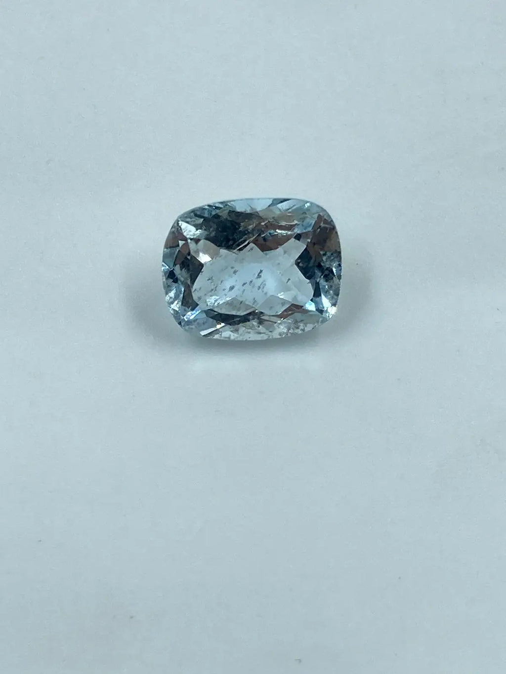 Cushion-cut aquamarine gemstone, sky blue, loose stone on light background