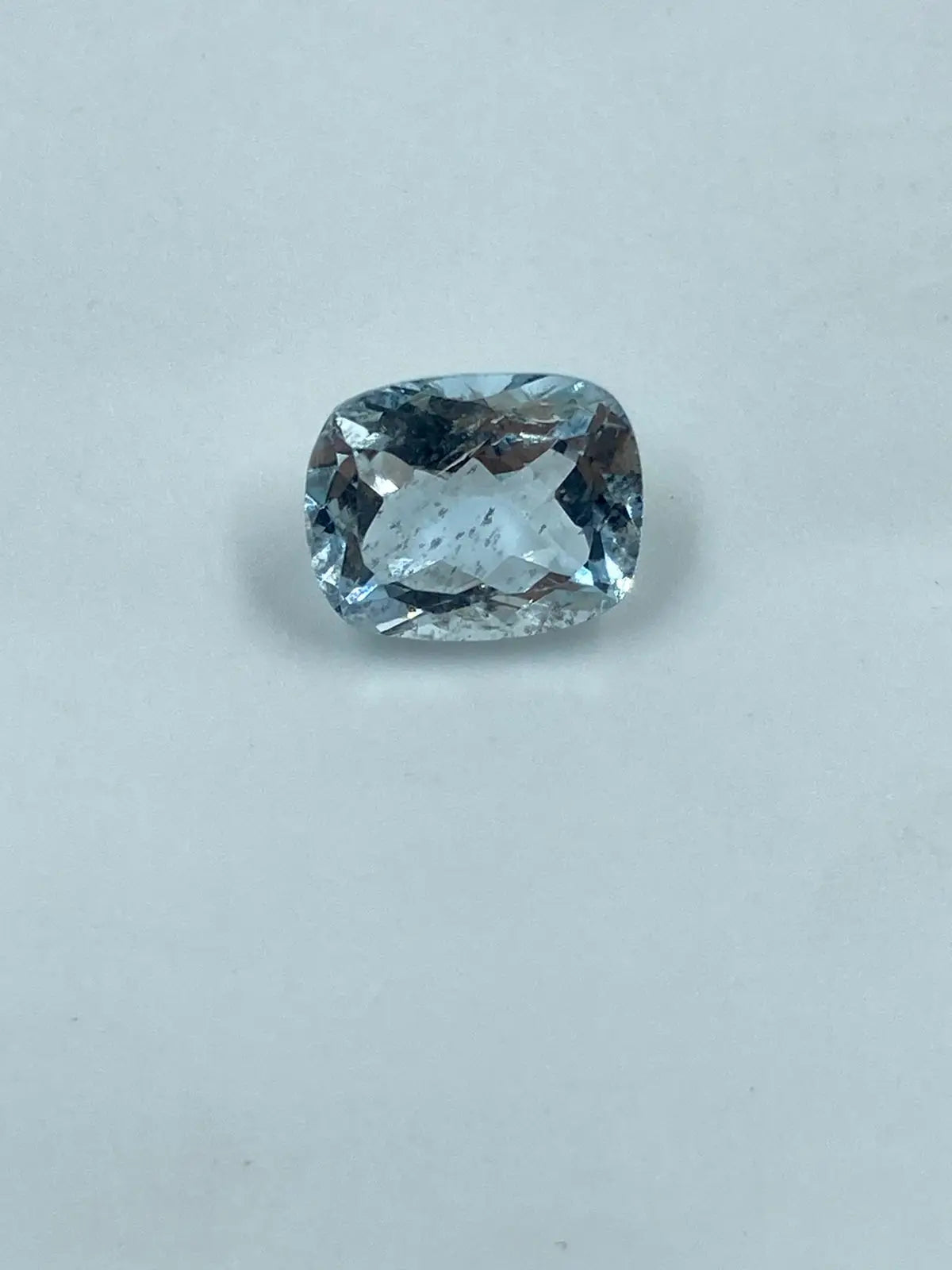 Cushion-cut aquamarine gemstone, sky blue, loose stone on light background
