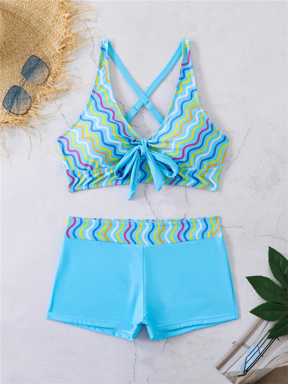 Tidesmit blue high-waisted bikini with a colorful wavy print, cross-back crop top, and front tie detail.