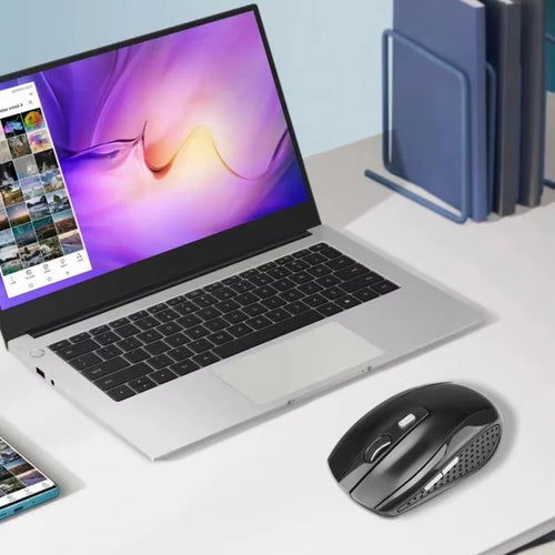 Black wireless ergonomic mouse with side buttons, scroll wheel, and DPI switch on a white desk next to a laptop.