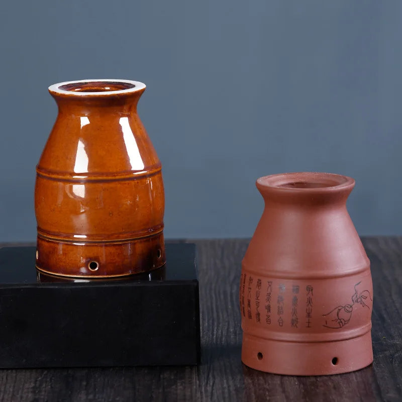 Two ceramic moxibustion burner cups: one glazed glossy brown, the other matte terracotta with calligraphy and art.