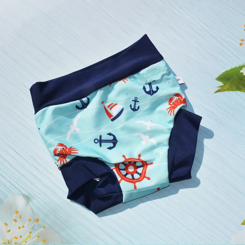 Small nautical print baby swim diaper with anchors, crabs, and sailboats on a light blue background.