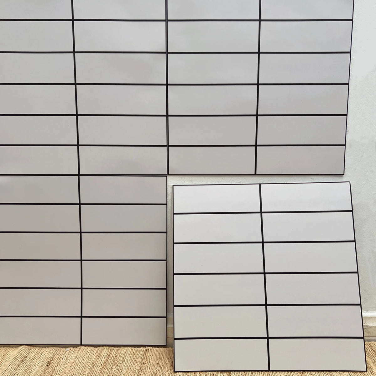 Light gray square peel-and-stick backsplash tile sheet with straight grout grid lines