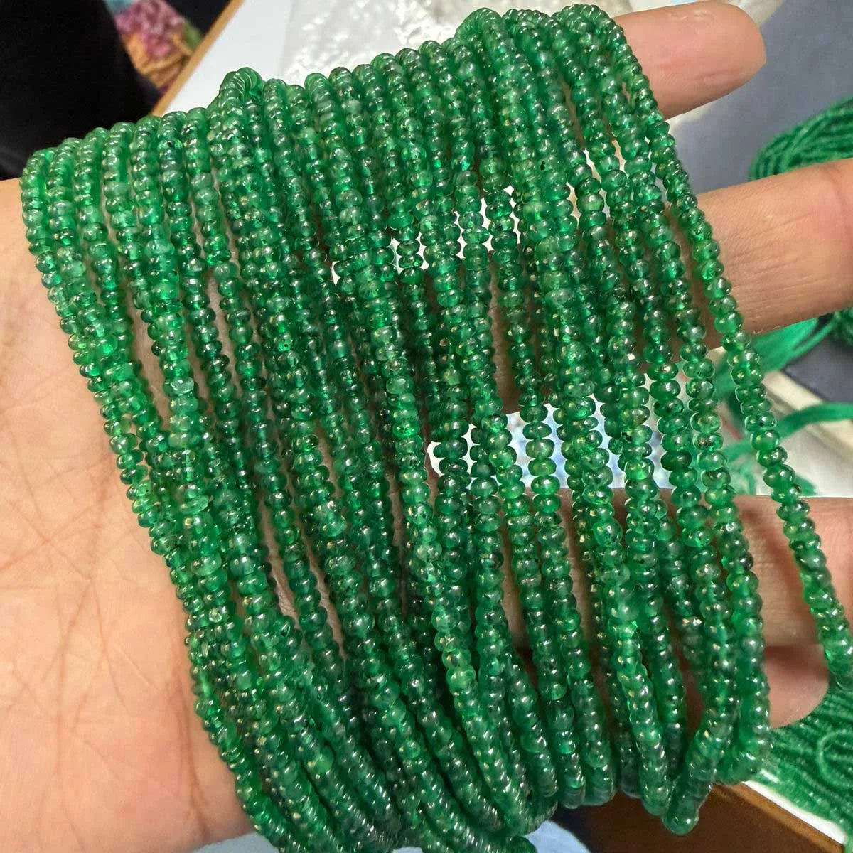 Strand of green smooth rondelle gemstone beads, held in hand
