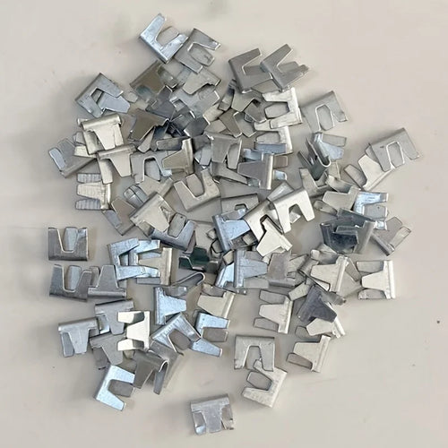 Silver stainless-steel cage fasteners, small metal clips scattered on surface