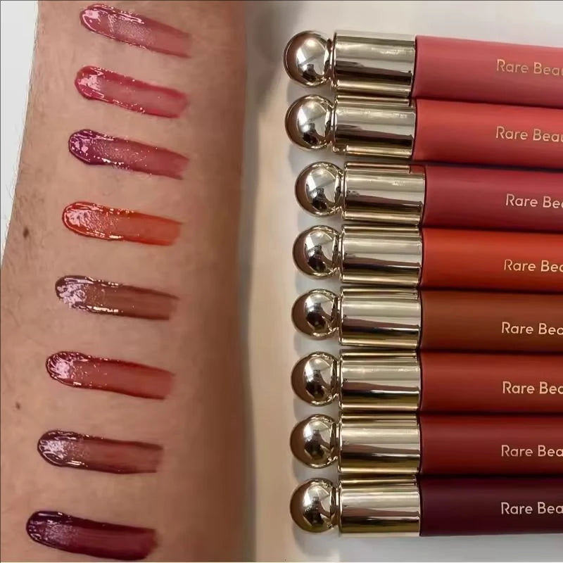 Rare Beauty Soft Pinch Tinted Lip Oil swatches showing glossy, long-lasting colors on skin with gold-capped applicators.