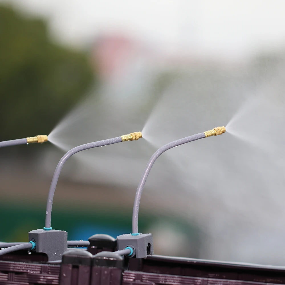 Misting irrigation nozzles spraying fine water from gray tubing across a garden row