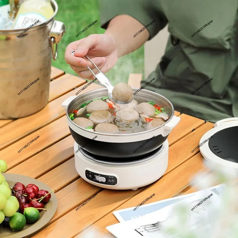 Electric cooking pot steaming with ingredients, black bowl on white base during simmering