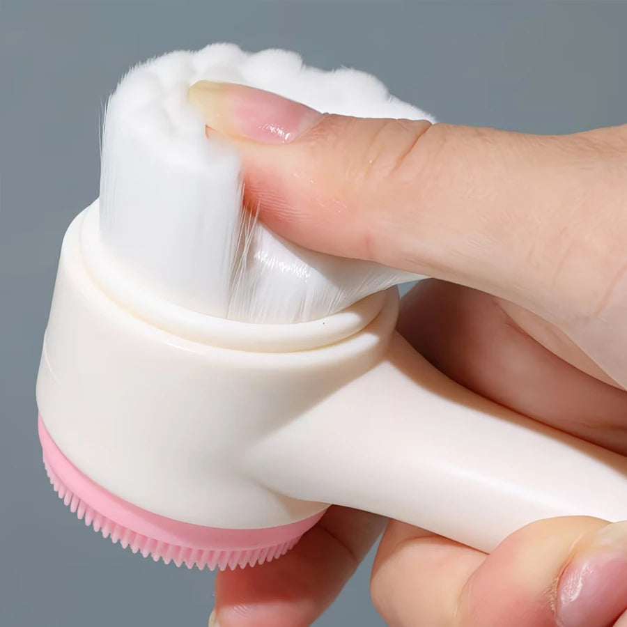 Double-sided manual facial cleansing brush with soft white bristles and pink silicone exfoliating scrubber for skincare.