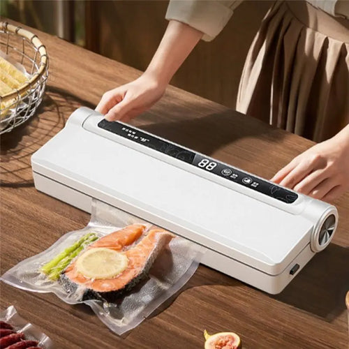 White automatic vacuum sealer sealing food bag on a wooden table with hands