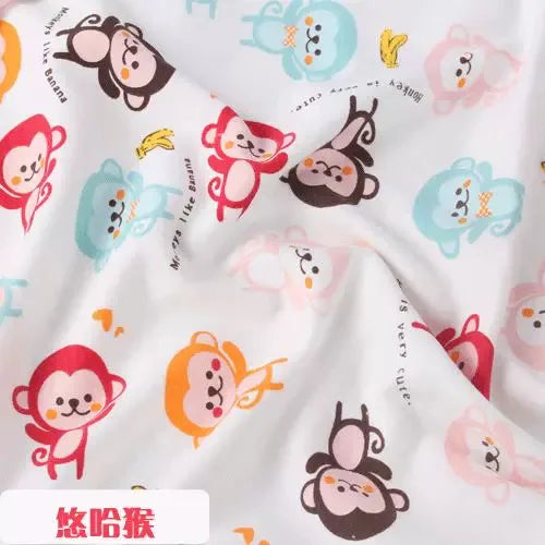 Soft white knit jersey fabric featuring a colorful repeating print of cute monkeys and bananas for baby clothing.