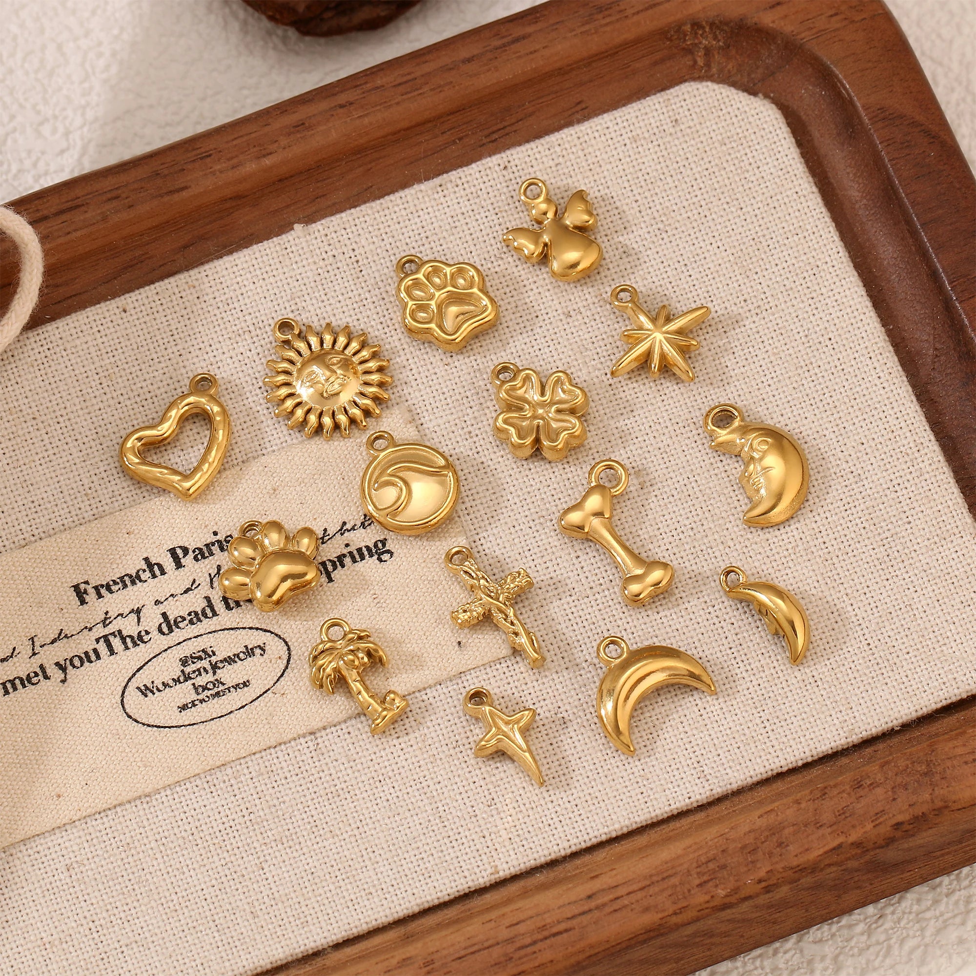 Gold stainless steel pet-themed charms including paw prints and bones for DIY pet jewelry making and craft projects.